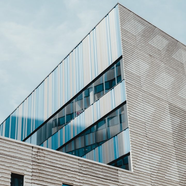 Moderne Gebäude mit einer schrägen Fassade und reflektierenden Fenstern.